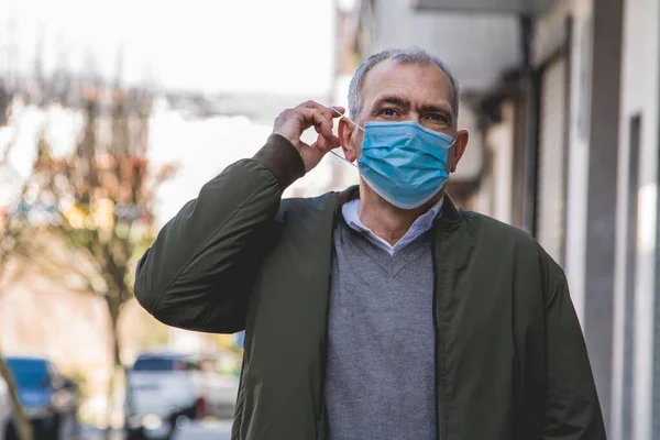 casual adult man with medical mask protecting from coronavirus around the city