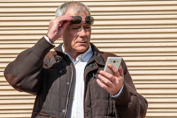 サングラスをかけた男が街中の携帯電話を使って — ストック写真