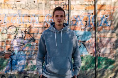 portrait of smiling man with sweatshirt on public wall with graffiti not subject to copyright