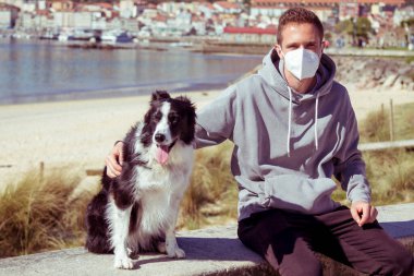 young man in medical mask with his dog in the new normal