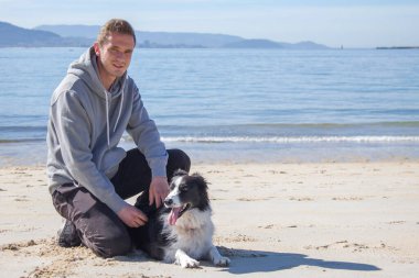 Plajda köpeğiyle genç bir adamın portresi.