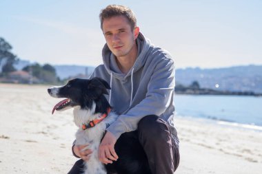Plajda köpeğiyle genç bir adamın portresi.