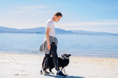 young man walking with his dog on the beach