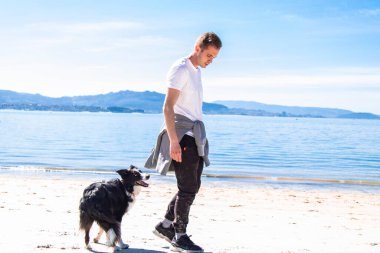 young man walking with his dog on the beach