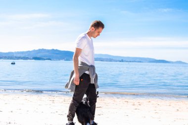 young man walking with his dog on the beach
