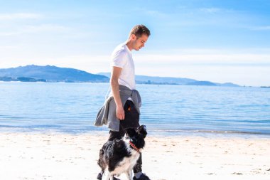 young man walking with his dog on the beach