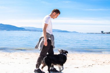 young man walking with his dog on the beach