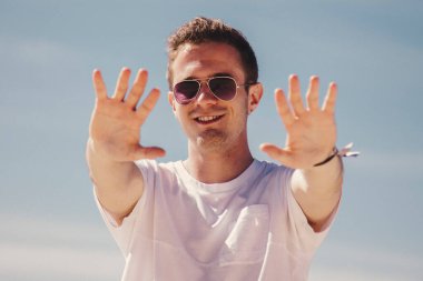 man in sunglasses walking on the beach and waving