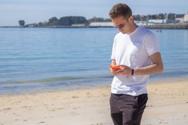 handsome man using mobile phone on the beach