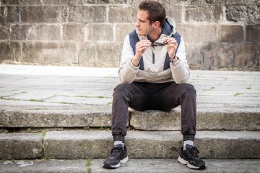 portrait of handsome man in sunglasses sitting on stairs