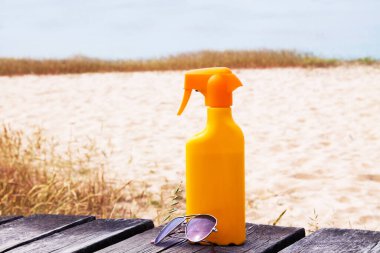 suntan lotion and sunglasses on the beach sand, summer vacation concept