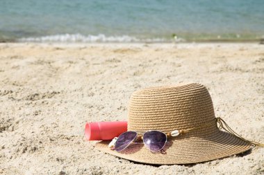 Sahilde güneş kremi ve şapka, yaz tatili ve rahatlama konsepti.