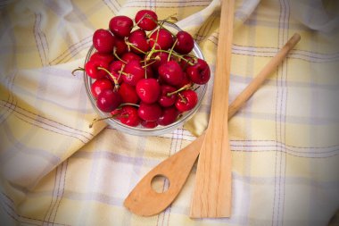 Masa örtüsü üzerinde kırmızı kirazlarla dolu bir kase.