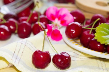 Damalı masa örtüsünde kırmızı kiraz tabağı