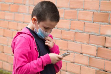 Cep telefonu kullanan tıbbi maskeli kız