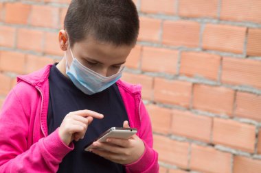Cep telefonu kullanan tıbbi maskeli kız