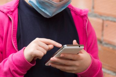 Tıbbi maskeli kız virüs ve enfeksiyonları önlemek için cep telefonu kullanıyor