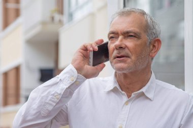 Şehirde cep telefonu kullanan kıdemli bir adam.