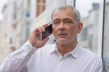 Şehirde cep telefonu kullanan kıdemli bir adam.