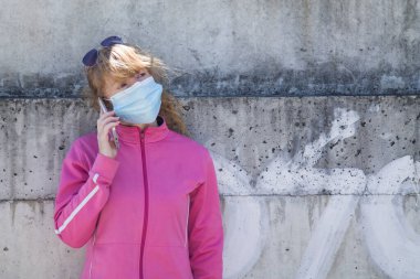 athlete woman with medical mask talking on the mobile phone