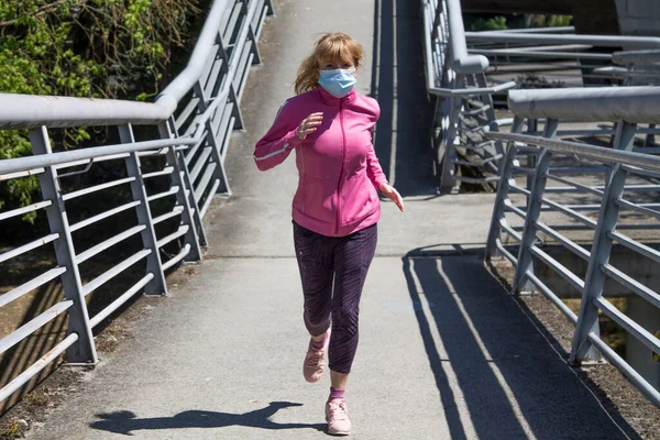 woman with medical mask running through the city, sport concept in the new normal