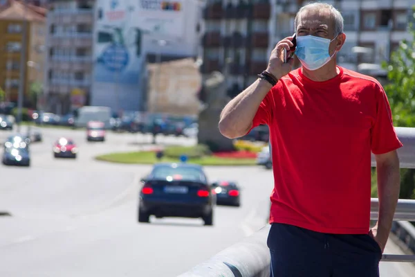 man with mobile phone and medical mask on the street, concept of new normal