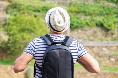 Sırt çantalı bir turist kırsalda yürüyor.