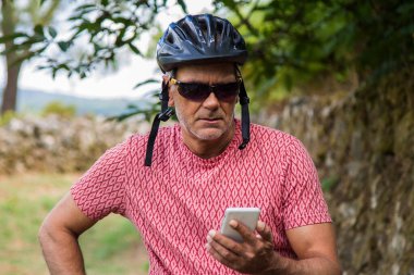 Bisikletli bir bisikletçi cep telefonunu kullanıyor.