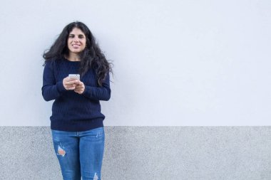 İzole edilmiş beyaz arka planda genç bir kadın cep telefonuyla mesaj gönderiyor.