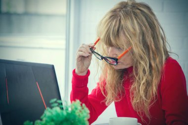 Evde ya da ofiste bilgisayarla çalışan olgun bir kadın.