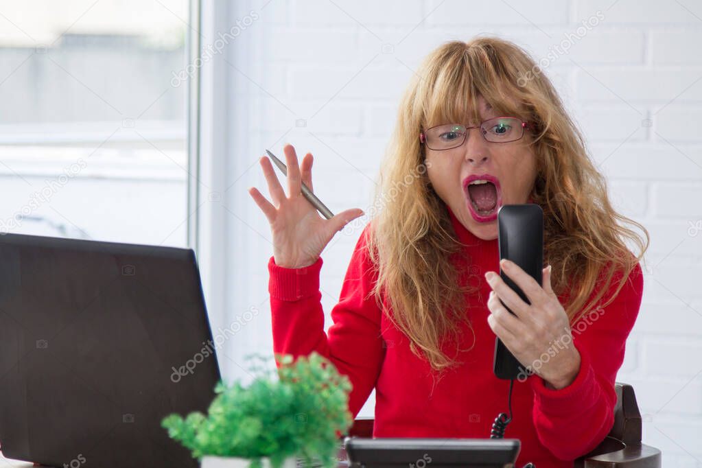 Stressed secretary shouting at the telephone receiver
