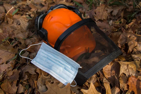 Arbetare Hjälm Bredvid Antivirala Mask Bakgrund Torra Blad Skogen — Stockfoto