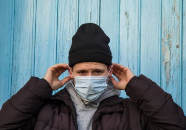 Adam yüzüne tek kullanımlık cerrahi maske takıyor.