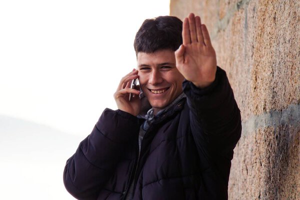 smiling man using smart phone on stone wall