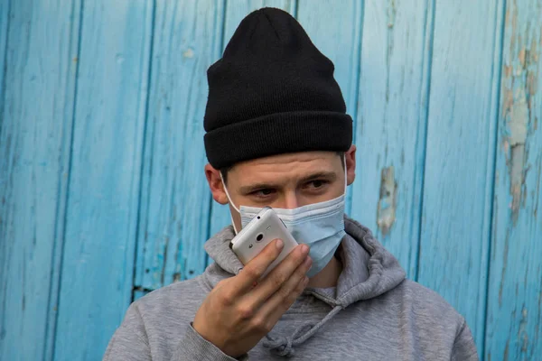 Jonge Man Met Wegwerp Chirurgisch Masker Praten Met Smart Phone — Stockfoto