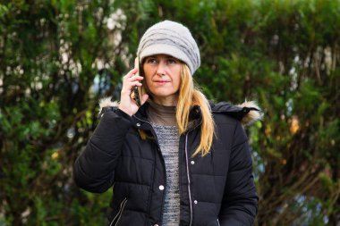 Olgun ya da orta yaşlı kadın şapkası ve cep telefonuyla gülümsüyor