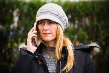 Şapkalı ve cep telefonlu gülümseyen kadın portresi