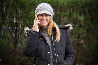 Şapkalı ve cep telefonlu gülümseyen kadın portresi