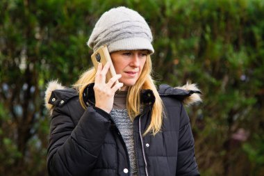 Şapkalı ve cep telefonlu gülümseyen kadın portresi