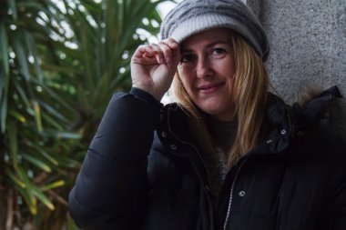 Şapkalı gülümseyen olgun bir kadının portresi.