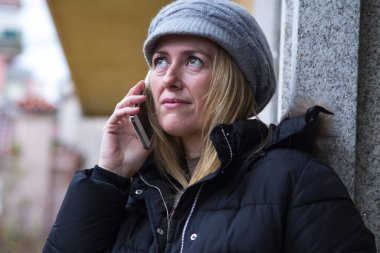 Şehirde akıllı telefon kullanan gülümseyen bir kadın.