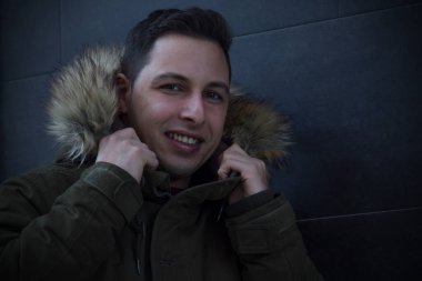 Siyah duvarında anorak olan çekici bir genç adam.