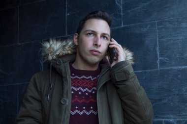 Adam sokak duvarında akıllı telefon kullanıyor.