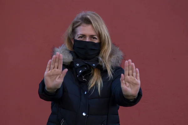 Woman with protection mask against coronavirus and covid-19 in denial attitude with hand