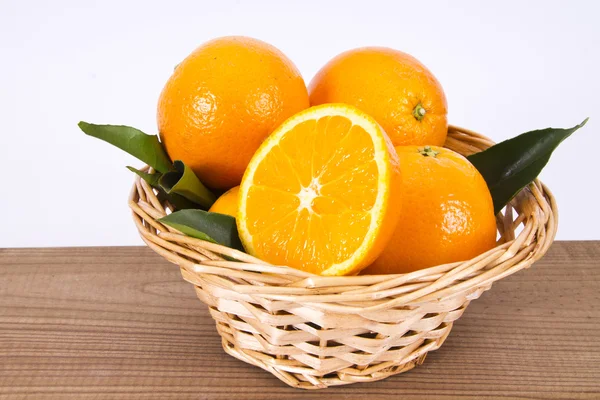 Basket of oranges on wooden board — Stock Photo, Image