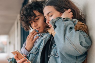 Sokaktaki mutlu gençler cep telefonlarına bakıyor.