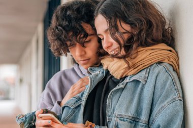 Sokaktaki mutlu gençler cep telefonlarına bakıyor.