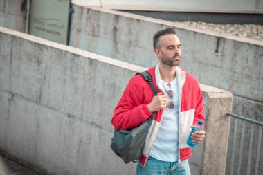 Sırt çantalı ve su şişeli genç adam şehir caddesinde