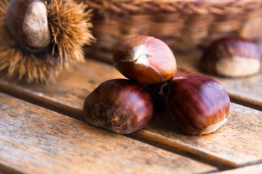 Kestaneler sonbahar yapraklarıyla ahşap arka planda 