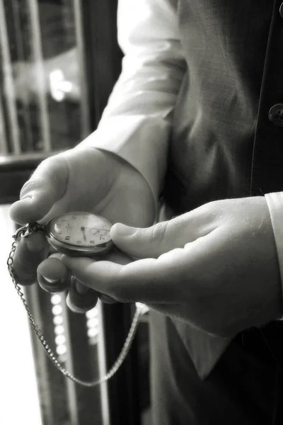 Detail of the hands of an elegant man looking at his pocket watch